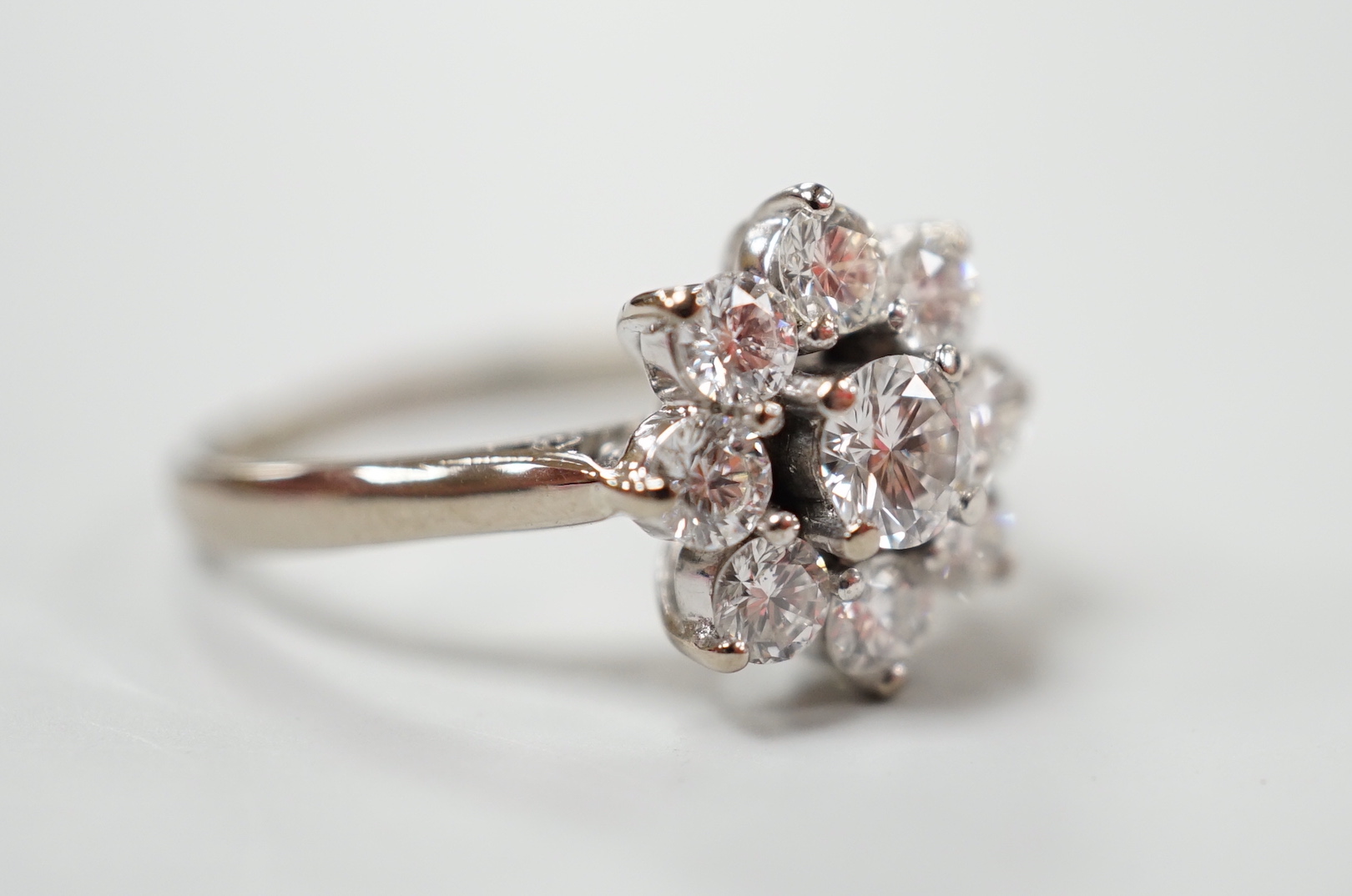 An 18ct, plat. and nine stone diamond set flower head cluster ring, the central stone weighing approximately 0.25ct, size O, gross weight 4 grams.